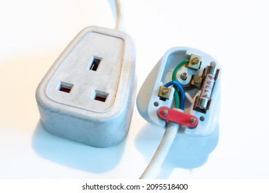 LONDON, UK - CIRCA 2021 DECEMBER: An open UK 13 amp wired plug with a white single trailing hard rubber socket, cluse-up. White background.