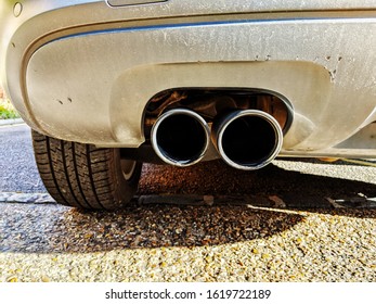 LONDON, UK - CIRCA JAN 2020: Exhaust Of A Big Car Whilst Stationary With Tire And Grey Bumper In View