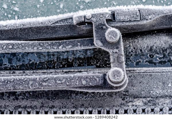 London, UK - Circa January 2019: Close-up view\
of part of a windshield wiper blade assembly seen frosted up during\
cold weather. Part of the win shielded is heavily iced up before\
being defrosted.
