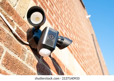 London, UK - Circa March 2022: Newly installed, Wireless Internet CCTV camera system seen with PIR detector and two high power LED floodlights. Located on a side entrance to a house.