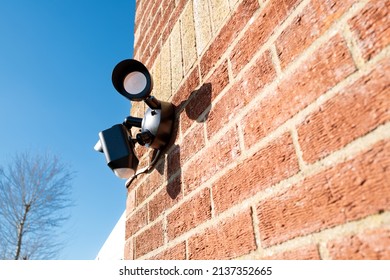 London, UK - Circa March 2022: Newly installed, Wireless Internet CCTV camera system seen with PIR detector and two high power LED floodlights. Located on a side entrance to a house.