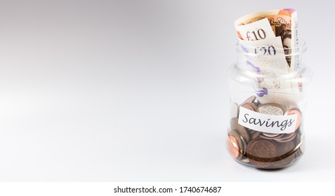 London, UK - CIRCA MAY 2020: Handful Of British Penny Coins And Polymer Currency Notes In A Jar On White Background With Copyspace