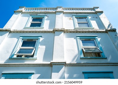 London, UK - Circa May 2022: Vertical View Of A Multi Storey Victorian House Used As Flats. Some Of The Exterior Paint Is Seen Peeling On The Walls And Window Sills.