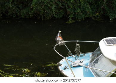 London, UK - Circa September 2021: Traditional pirate flag seen flying at the front of a small river boat. Seen moored up by the side of an English inland waterway at a private location.