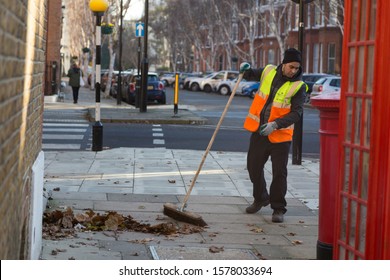 London, UK - December 03, 2019: London Street Cleaner Sweeping Fallen Leaves