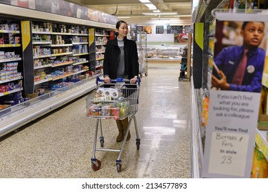 London, UK - December 12, 2014: A shopper browses an aisle of a Tesco supermarket store. Britain's Tesco is the world's third largest supermarket chain after America's Walmart and France's Carrefour.