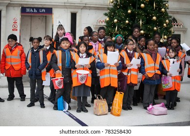 London, UK - December 22, 2017: Children In Orange Waistcoats Sing Christmas Carols, Collect Money For Charity