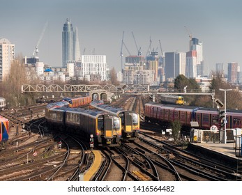 London, UK, England - 2/22/2019: Trains Approach Clapham Junction Rail Station With London City Skyline In Background