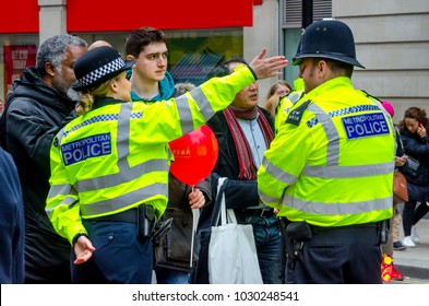 LONDON, UK - FEB. 18, 2018: Lady Police And His Officer Helping Members Of The People In A Street Of London To Find Their Way.