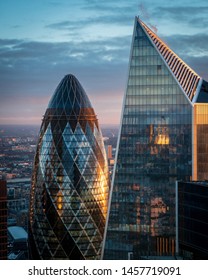 LONDON, UK - FEBRUARY 11, 2019: The golden rays of sunrise hitting the side of the Gherkin and Scalpel buildings in the city of London