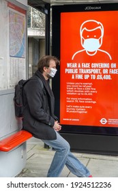 London, UK - February 20 2021: London Bus Shelter With Face Mask Warnings, Person Wearing A Face Cover, Pimlico, London