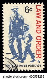 London, UK, February 5 2011 - Vintage 1968 United States Of America Cancelled Postage Stamp  Showing An Image Of  Law And  Order With A Police Officer Assisting A Young Child