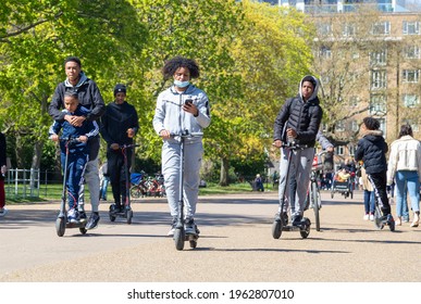 London, UK - Group of black teenagers crossing a London park on electric scooters.