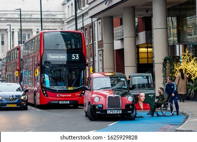 London, UK - January 1, 2020: A taxi driver helps a person with a wheelchair get in a taxi