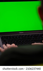 London, UK - January 12, 2022. Caucasian Man Uses MacBook Air M1. Person Is Working On Latest Apple Laptop With Greenscreen Of Chromakey Mockup. Green Screen And Chroma Key.