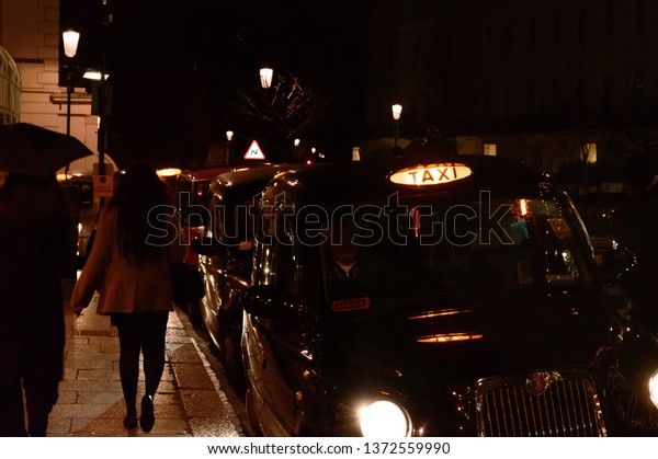 London,\
Uk, january 2019. Night city view, a characteristic detail of the\
busy city life, taxis, people and wet\
streets.