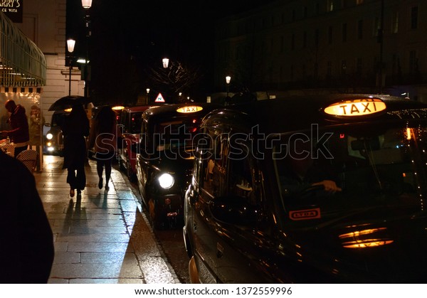 London,
Uk, january 2019. Night city view, a characteristic detail of the
busy city life, taxis, people and wet
streets.