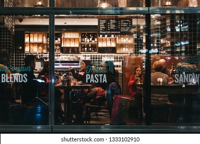 London, UK - January 26, 2019: People inside Italian restaurant in Canary Wharf, view through the window from outside. Canary Wharf is a busy financial area of London that often host events. 