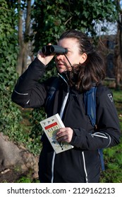 London, UK - January 5th 2022: Person Birdwatching With Binoculars And Reference Book