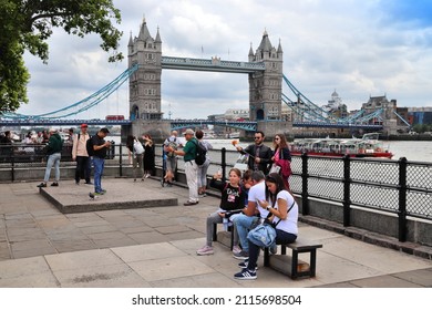 LONDON, UK - JULY 13, 2019: Tourists visit river Thames embankment in London with famous Tower Bridge in the skyline in background.