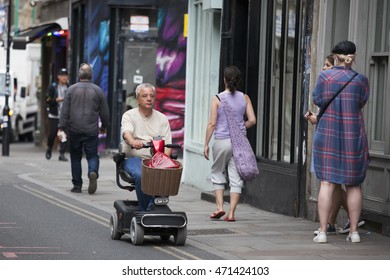 London, UK - July 17, 2016. Elderly man drive mobility scooter through the London street.