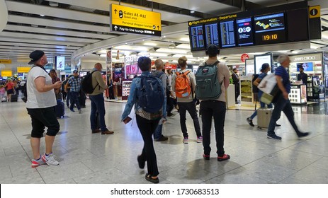 London, UK - July 18, 2019: Air Travelers Check A Departures Board At A Busy Heahthrow Airport Terminal. Heathrow Is One Of The Busiest Airports In The World And Busiest In Europe By Passenger Volume.
