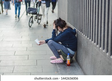 London, UK, July 2, 2019: Young Homeless Woman Holding A Glass Is Begging For Money And Help