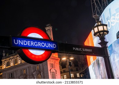 London, UK. July 20, 2021. Illuminated Underground Public Subway Sign With City Building And Streetlight At Night