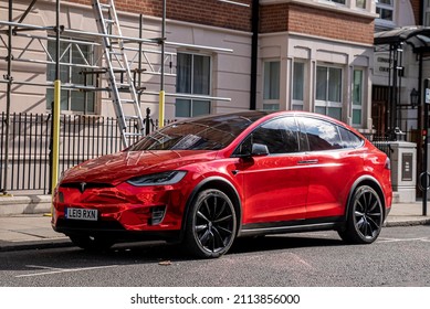 London, UK. July 20, 2021. Red Modern Tesla Car Model Parked At Roadside Next To A Residential Building