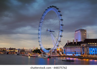 LONDON, UK - JULY 21, 2014: London eye in the night and south bank of river Thames, famous London's walk and tourist destination