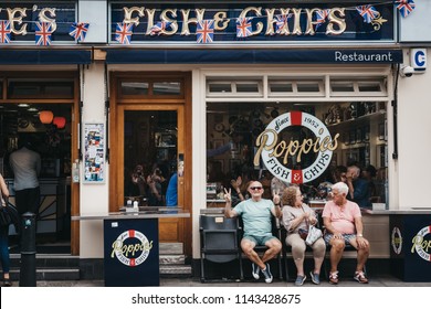 London, UK - July 22, 2018: People sitting on a bench outside Poppie's in Spitalfields, London, a famous fish & chips shop that has been serving since 1952. 