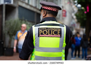 LONDON, UK - JULY 28, 2022.  A Rear View Of A Metropolitan Policeman In Uniform And On The Street With A City Of London Police Sign On His Back