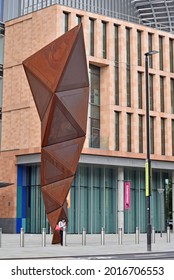 London, UK - July 3rd 2021: Commuter Stands By The Paradigm Sculpture Beside St Pancras Train Station