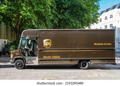 London, UK - July 5, 2022: Closeup, UPS Brown Delivery Electric Van In Albany Street, Driver On Seat, Backed By Green Foliage.