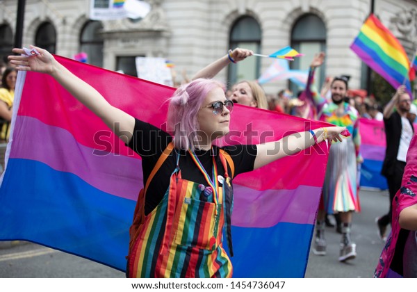 LONDON, UK - July 6th 2019: A\
person hods a bisexual pride flag at a gay pride march in\
London