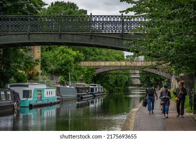 London, UK - Jun 09 2022: People Walking On The Sidewalk Of Regent's Canal, While Narrowboats Floating On The Water; London Everyday Life