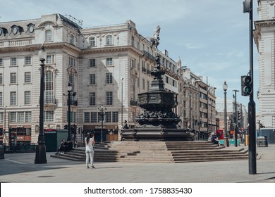 London, UK - June 13, 2020: Woman taking photo of Eros statue in empty Piccadilly Circus, one of the most popular and typically very busy tourist areas in London, UK.