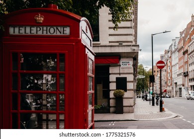 London, UK - June 14, 2020; Red telephone box out of focus, street name sign on Mayfair Place, City of Westminster. Mayfair remains one of the most expensive places to live in London and the world.