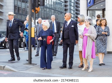 London, UK - June 21, 2022: Group of elderly people dressed for event crossing the road in the City of London. Commuters, office workers, City of London life, Street photography