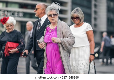 London, UK - June 21, 2022: Group of elderly people dressed for event crossing the road in the City of London. Commuters, office workers, City of London life, Street photography