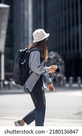 London, UK - June 21, 2022: Young woman with mobile phone is walking in the City of London street. City of London financial and business area life, street photography