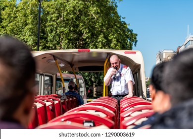 London, UK - June 22, 2018: Top of Big Bus double decker with guided tour guide speaking on microphone and tourists sitting in seats