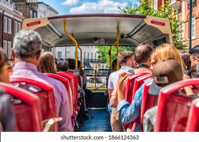 London, UK - June 22, 2018: Back of people tourists sitting in seats looking at view of city on street road double decker red big bus