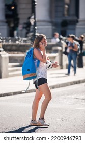 London, UK - June 22, 2022: Young Woman With Rucksack Is Walking In  The City Of London. People Rush At Work 