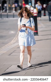 London, UK - June 22, 2022: Young Woman With Rucksack Is Walking In  The City Of London. People Rush At Work 