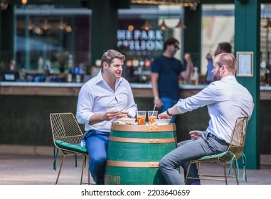 London, UK - June 22, 2022: Group Of Young Professional People  Having A Chat In Park Cafe In The City Of London. Business Life In The City.