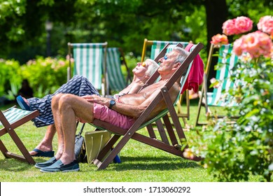 London, UK - June 24, 2018: Queen Mary's Rose Gardens In Regent's Park During Sunny Summer Day With Senior Old People Couple Sunbathing On Lounge Chair