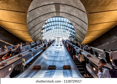 London, UK - June 26, 2018: People crowd commuters riding escalators up inside Underground tube metro during morning commute in Canary Wharf with modern architecture