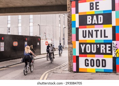 London, UK - June 28 2015: Group Of Urban Cyclists Riding Next To A Big Colored Billboard With The Words 