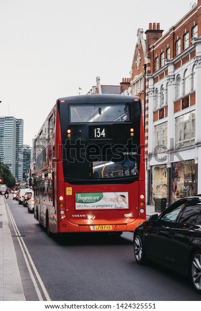 London, UK - June 5,\
2019: Red double decker bus and cars queuing in traffic on\
Tottenham Court Road, London. Buses are an integral part of\
Transport for London\
network.